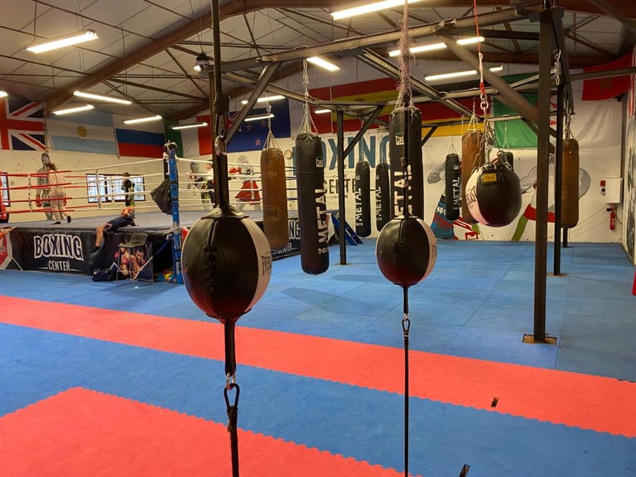 Les poires de vitesse au premier plan, les sacs alignés au fond et le ring sous les drapeaux du plafond.